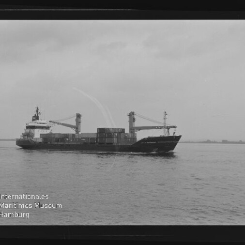 Containerschiff mit zwei Ladekränen und gestapelten Containern fährt auf ruhigem Wasser; Museumslogo links unten.