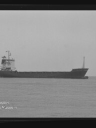Frachtschiff in Seitenansicht auf ruhiger See, Schwarzweiß-Aufnahme mit sichtbarem AGFA PAN 100-Filmrand und Museumslogo.