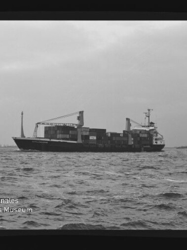 Containerfrachter mit Containern und Ladekränen auf ruhiger See; Museumslogo unten links.