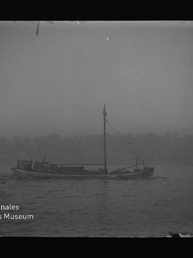 Kleines Frachtschiff mit Mast als Silhouette auf nebligem Wasser, mit Wasserzeichen 'Maritimes Museum Hamburg'.