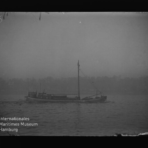 Kleines Frachtschiff mit Mast als Silhouette auf nebligem Wasser, mit Wasserzeichen 'Maritimes Museum Hamburg'.