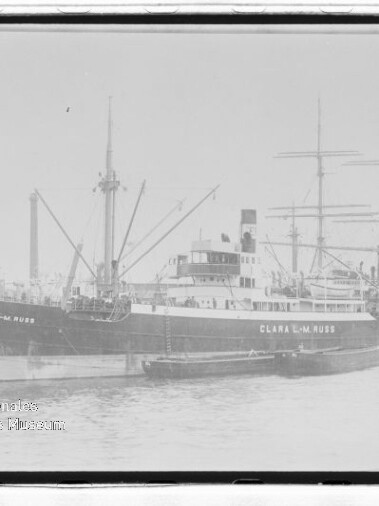 Schwarzweißaufnahme eines am Kai liegenden Frachtschiffs CLARA L.M. RUSS mit Masten, Ladebaum und Beiboot.