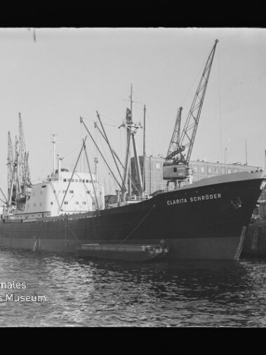 Frachtschiff Clarita Schröder am Kai eines Industriehafens, mehrere Hafenkräne im Hintergrund.
