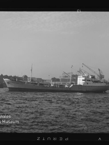 Frachtschiff auf der Elbe vor dem Hamburger Hafen mit mehreren Hafenkränen und leicht welliger Wasseroberfläche.