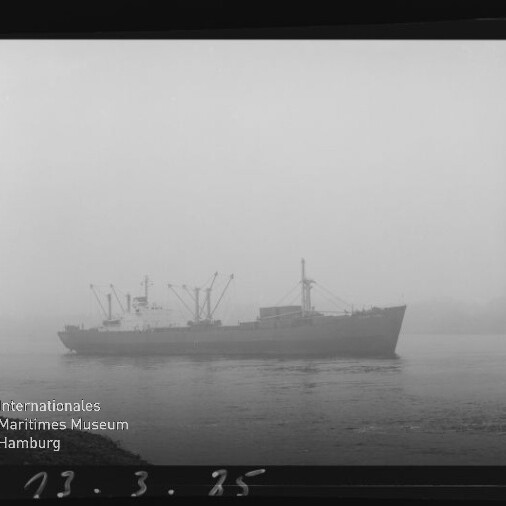 Frachtschiff im dichten Nebel auf ruhigem Wasser, mit Internationales Maritimes Museum Hamburg‑Logo unten links.
