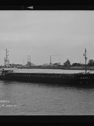 Frachtschiff 'CLAUDIA L' auf einem Fluss vor industriellem Ufer, Schwarzweißaufnahme mit Museumslogo