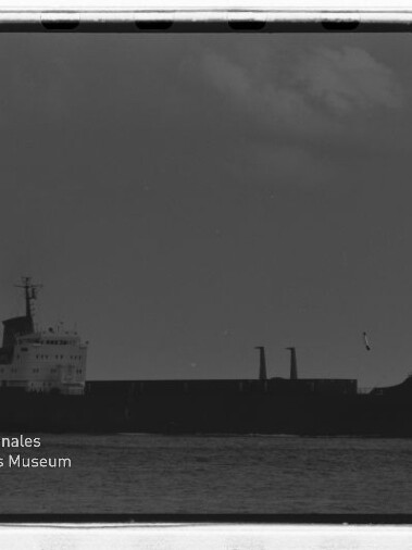 Silhouette eines Frachtschiffs am Horizont auf ruhiger See, schwarzweiße Negativaufnahme mit dem Schriftzug Internationales Maritimes Museum Hamburg