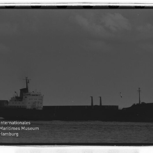 Silhouette eines Frachtschiffs am Horizont auf ruhiger See, schwarzweiße Negativaufnahme mit dem Schriftzug Internationales Maritimes Museum Hamburg