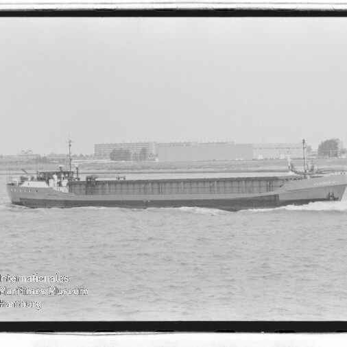 Schwarzweiß-Frachtschiff fährt auf ruhiger See vor flachem Industrie- und Stadthorizont mit ersichtlichem Museumswasserzeichen.