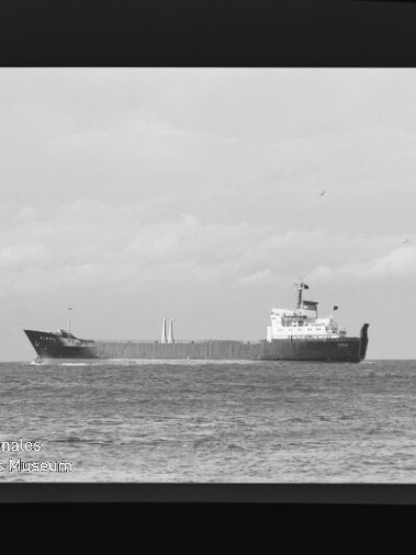 Bulkfrachter fährt in ruhiger See, schwarzweiß-Foto mit Filmrand und Schriftzug Internationales Maritimes Museum Hamburg.