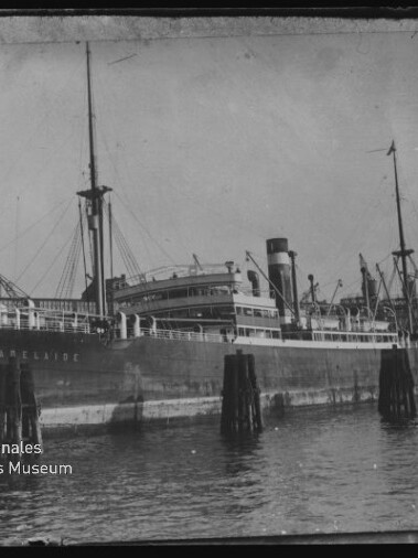 Frachtschiff mit Masten und Schornstein am Kai, Pfähle im Wasser und Logo Internationales Maritimes Museum Hamburg
