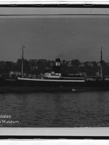 Frachtschiff mit Schornstein und zwei Masten vor einem Ufer mit Häusern, unten links Schriftzug Maritimes Museum Hamburg.
