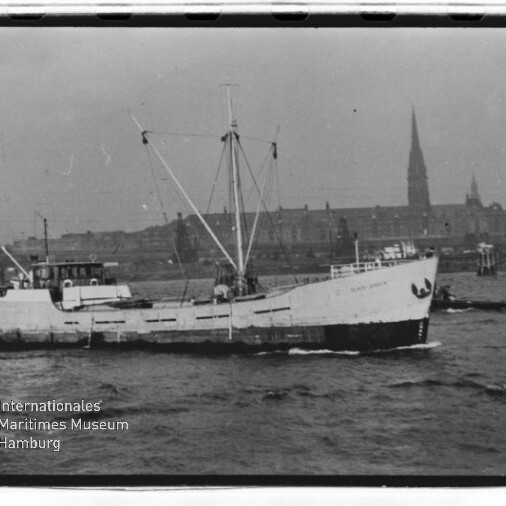 Kleiner Frachter fährt auf der Elbe vor der Hamburger Ufer-Silhouette mit hohem Kirchturm; Museumslogo unten links.