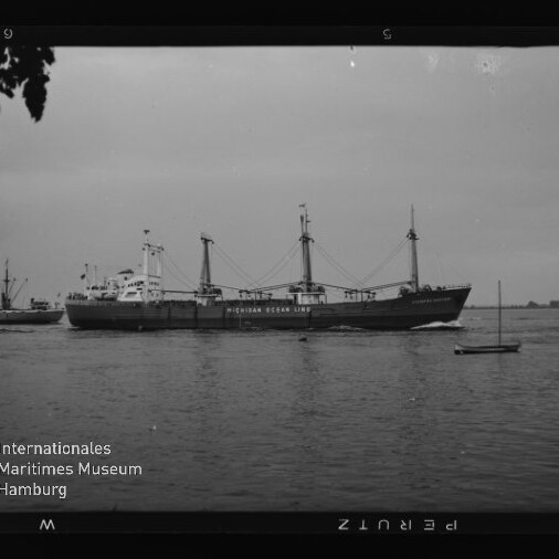 Frachtschiff der Indian Ocean Line auf ruhigem Wasser, ein kleines Segelboot daneben und weitere Schiffe am Horizont.