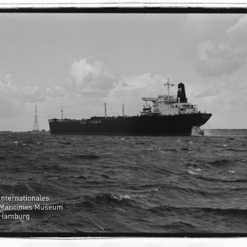 Großes Frachtschiff auf bewegter See, schwarz-weiß, mit Museumslogo Internationales Maritimes Museum Hamburg unten links.