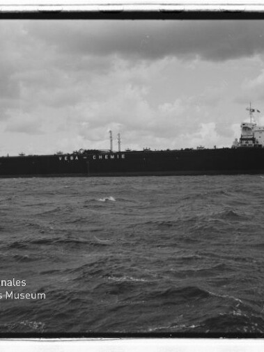 Schwarzweißaufnahme eines großen Tankers mit der Aufschrift VEBA-CHEMIE auf dem Rumpf, ruhige See und wolkiger Himmel.