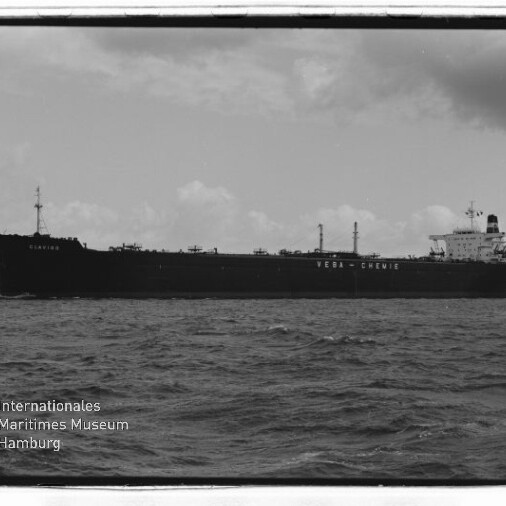 Schwarzweißfoto eines großen Tankers mit der Aufschrift VEBA‑CHEMIE auf dem Rumpf, auf offener See mit Museumslogo unten links.