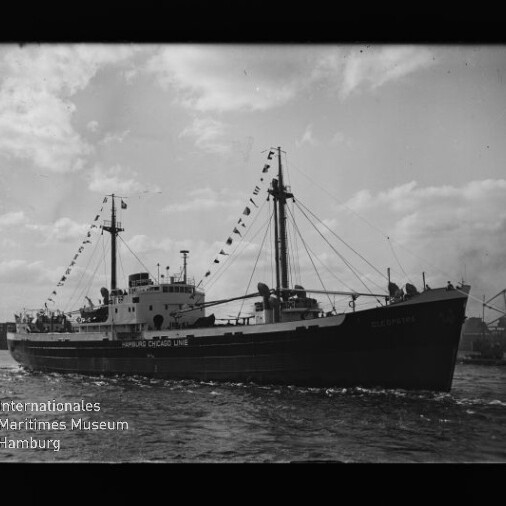 Frachtschiff mit zwei Masten und Signalwimpeln, Schriftzug 