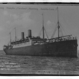 Zweischornsteiniger Passagierdampfer Cleveland der Hamburg-Amerika Linie auf ruhiger See, schwarzweißes Postkartenfoto.