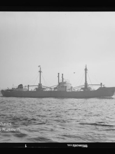 Frachtschiff mit zwei Masten und Ladebäumen auf ruhiger See, Wasserzeichen des Internationalen Maritimen Museums Hamburg.