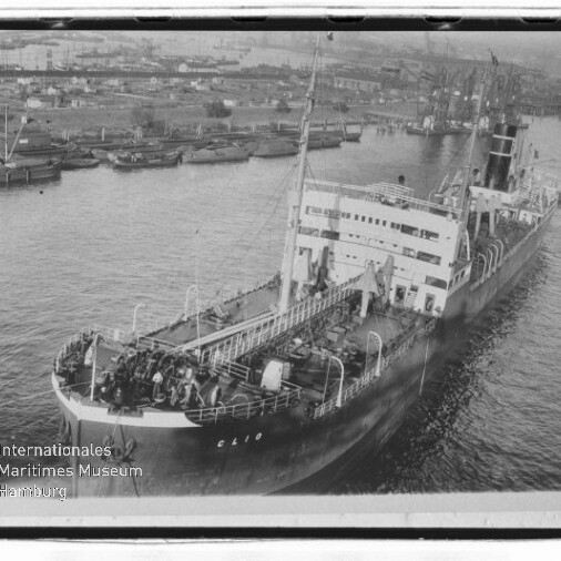 Großes Frachtschiff mit sichtbarem Namenszug 'Clio' fährt in einen Hafen mit Kränen; Museumswasserzeichen unten links.