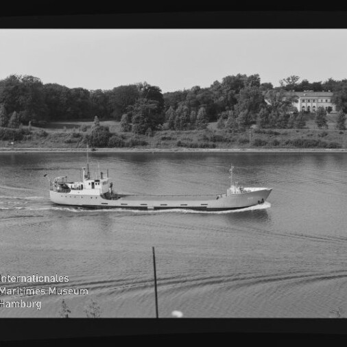 Kleiner Frachter auf ruhigem Fluss vor bewaldetem Ufer; Schwarzweißbild mit Maritimen-Museum-Wasserzeichen.