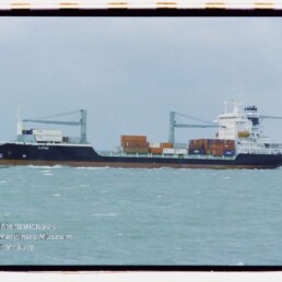 Containerschiff mit zwei Kränen und Containern auf ruhiger See unter bewölktem Himmel; Wasserzeichen Museum Hamburg