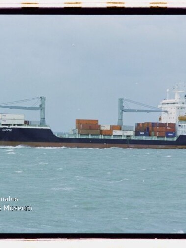 Containerschiff mit zwei Kränen und Containern auf ruhiger See unter bewölktem Himmel; Wasserzeichen Museum Hamburg