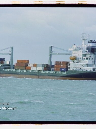 Containerschiff mit Containern und zwei Ladekränen auf ruhiger See bei grauem Himmel; Wasserzeichen Maritimes Museum.