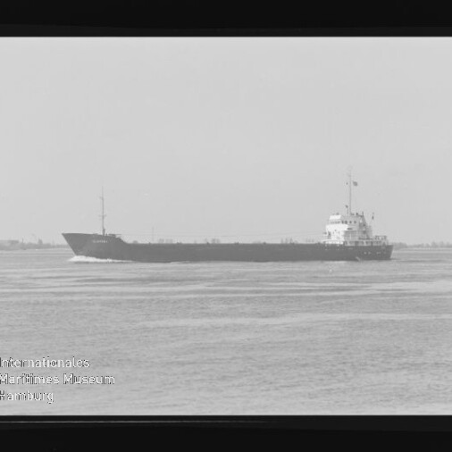 Frachtschiff in Seitenansicht auf ruhigem Meer vor flachem Horizont, schwarzweiß mit Museumswasserzeichen unten links.