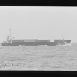 Schwarzweißfoto eines Frachtschiffs bei Seegang, Filmrand und Schriftzug Internationales Maritimes Museum Hamburg sichtbar.