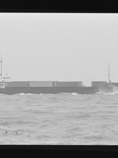 Schwarzweißfoto eines Frachtschiffs bei Seegang, Filmrand und Schriftzug Internationales Maritimes Museum Hamburg sichtbar.