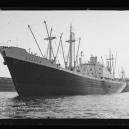 Großes Frachtschiff CLIVIA mit mehreren Ladekränen im Hafen, seitliche Aufnahme nahe der Wasserlinie.