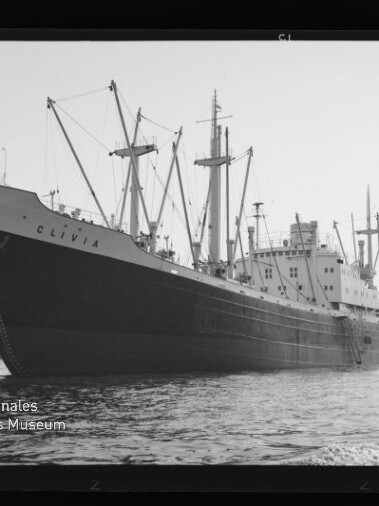 Großes Frachtschiff CLIVIA mit mehreren Ladekränen im Hafen, seitliche Aufnahme nahe der Wasserlinie.