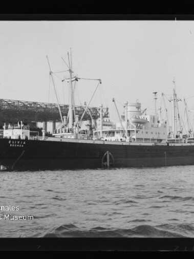 Frachtschiff Oliva am Kai vor einer Hafenanlage mit Kränen und Wasser im Vordergrund