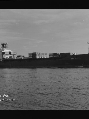 Containerschiff mit gestapelten Containern auf ruhigem Wasser, schwarzweiß, Museumslogo unten links