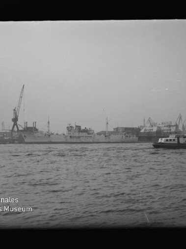 Hafenpanorama mit Schiffen, Kränen und einer kleinen Fähre; sichtbarer Schriftzug: Internationales Maritimes Museum Hamburg.