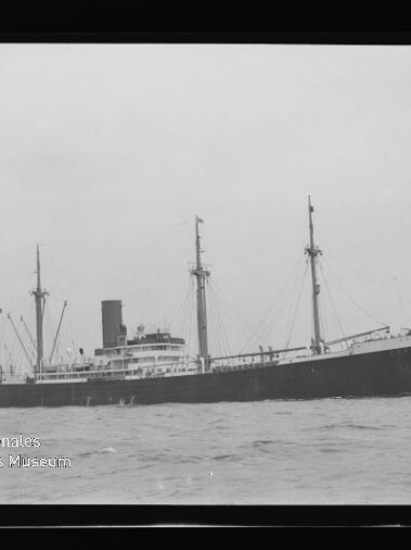 Schwarz-weißes Frachtschiff mit mehreren Masten, Ladebäumen und mittigem Schornstein auf ruhiger See; Wasserzeichen 