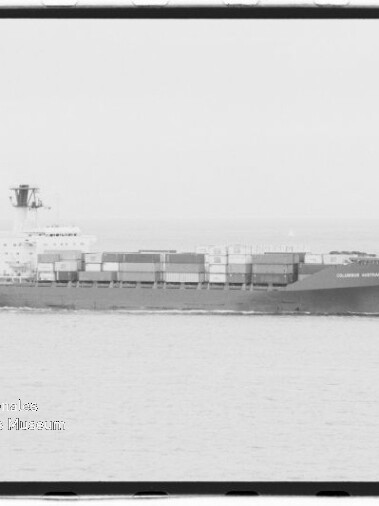 Schwarzweiß-Seitenansicht eines großen Containerschiffs mit gestapelten Frachtcontainern und markanter Aufbauten am Heck, das ruhig über das offene Meer fährt; links unten ist ein Wasserzeichen des Internationalen Maritimen Museums Hamburg zu sehen.