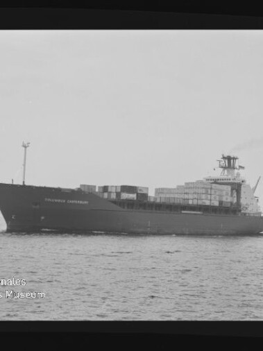 Schwarzweiß-Aufnahme eines großen Containerschiffs in Seitenansicht auf ruhiger See mit gestapelten Containercontainern, Aufbauten und leichtem Rauch aus dem Schornstein; Filmrahmen und Museumswasserzeichen unten links sind sichtbar.