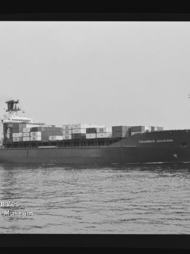 Schwarzweiß-Foto eines Containerschiffs „COLUMBUS LOUISIANA“ in Seitenansicht auf ruhiger See, mit gestapelten Containern auf dem Deck, sichtbarem Filmrand und Wasserzeichen des Internationalen Maritimen Museums Hamburg.