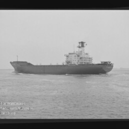 Schwarzweiß-Fotografie eines großen Frachtschiffs auf ruhiger See, seitliche Ansicht mit markanten Aufbauten und Schornstein, umgeben vom sichtbaren Filmrand mit 'AGFA PAN'-Aufdruck und Wasserzeichen des Internationalen Maritimen Museums Hamburg.