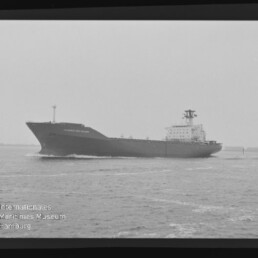 Schwarzweißaufnahme eines großen Frachters/Tankers im Seitenprofil auf leicht bewegter See, mit sichtbarem Filmrand und der Nummer 6 links sowie dem Wasserzeichen «Internationales Maritimes Museum Hamburg» unten links.