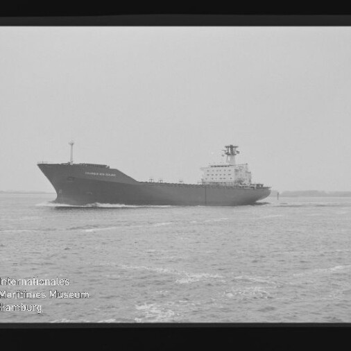Schwarzweiß-Foto eines großen Frachtschiffs, das von links nach rechts über ruhige See fährt; sichtbarer Filmrand mit der Ziffer 5 und Museumsstempel des Internationalen Maritimen Museums Hamburg unten links.