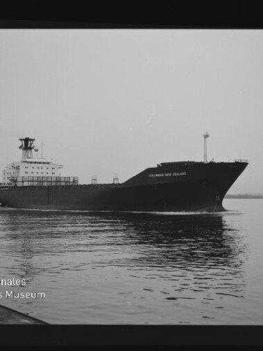 Schwarzweißaufnahme eines Frachtschiffs mit markantem Bug und achterlichem Aufbau, das ruhig über spiegelndes Wasser fährt; links unten Stempel des Internationalen Maritimen Museums Hamburg.