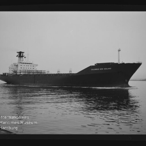 Schwarzweißaufnahme des Frachtschiffs Columbus New Zealand, seitlich auf ruhigem Wasser fahrend, mit Aufbau und Schornstein links sowie dem Schriftzug und Logo des Internationalen Maritimen Museums Hamburg unten links.
