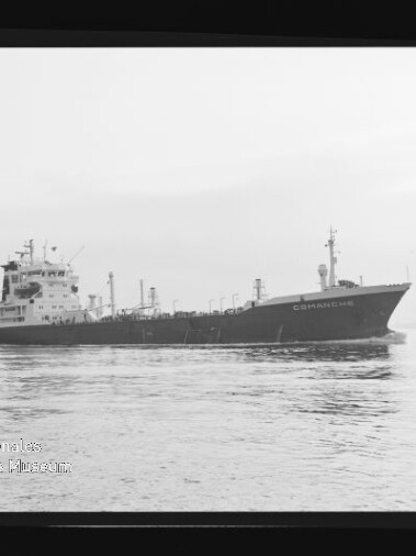 Schwarzweiß-Aufnahme des Tankschiffs Comanche in Seitenansicht auf ruhiger See, mit achteren Aufbauten, langem Tankdeck und Masten; Foto ist von dunklem Negativrand umrahmt und zeigt das Logo des Internationalen Maritimen Museums Hamburg.