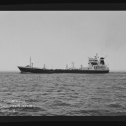 Schwarzweiß-Foto eines seitlich sichtbaren Tankschiffs auf ruhiger See mit sichtbarem Filmrand und dem Wasserzeichen „Internationales Maritimes Museum Hamburg“ unten links.