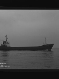 Schwarzweiß-Foto eines Frachtschiffs in Seitenansicht auf ruhiger See unter bedecktem Himmel; am unteren linken Bildrand sichtbar das Wasserzeichen „Internationales Maritimes Museum Hamburg“ sowie Filmränder mit Ziffern.