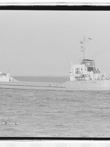 Schwarz-weiße Aufnahme zweier Frachtschiffe auf ruhiger See: im Vordergrund ein langes Frachtschiff mit Aufbauten am Heck und Schornstein mit Logo, im Hintergrund links ein weiteres Schiff; unten links Schriftzug des Internationalen Maritimen Museums Hamburg und sichtbarer Negativrahmen.